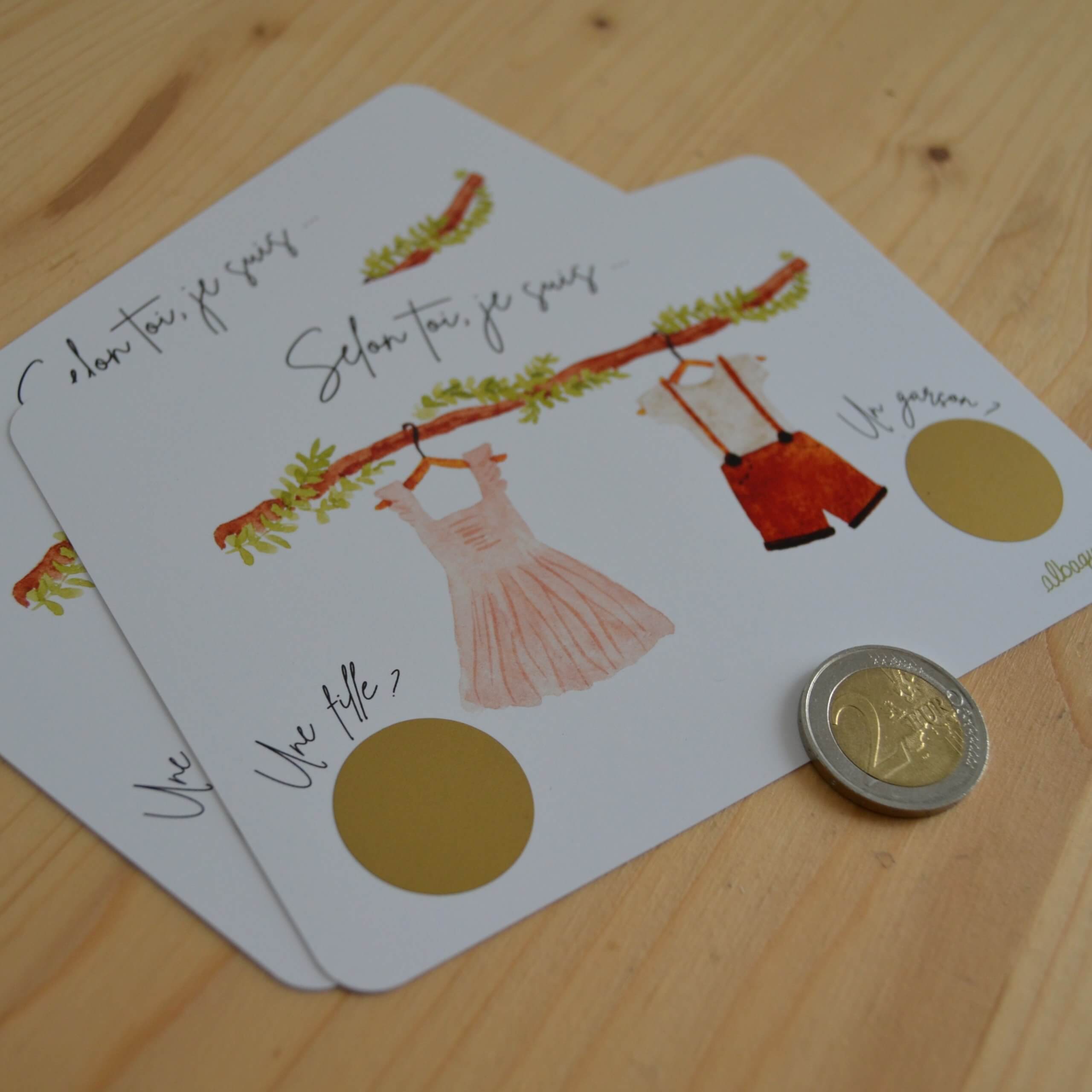 cartes à gratter pour annoncer le sexe de bébé avec une illustration à l'aquarelle d'une petite robe et d'une salopette.